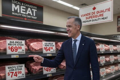 Canada Prime Minister Mark Carney standing in front of a grocery store meat case.