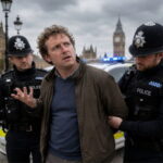 UK police officers detaining a white British man on a London street.