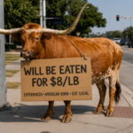 Texas longhorn cow cattle with a sign around its neck standing on a street corner.