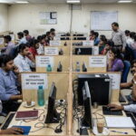 India scam call center with male and female workers on phones.
