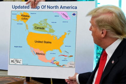 Donald Trump at his desk holding a map of North America.