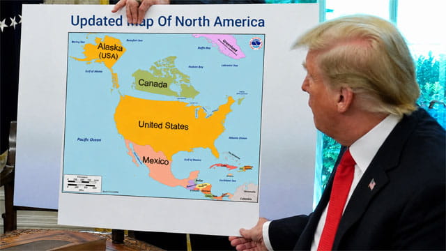 Donald Trump at his desk holding a map of North America.