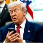 Donald Trump checking Siri on his smartphone at White House desk.