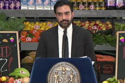 Zohran Mamdani giving a speech inside supermarket on grocery stores.