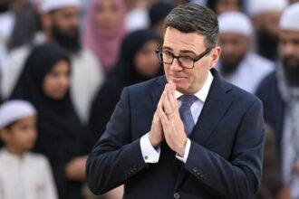 UK Prime Minister Andy Burnham standing in front of Muslim voters.