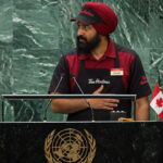 Indian Punjabi man wearing a Tim Horton's uniform giving a speech at the United Nations for Canada.