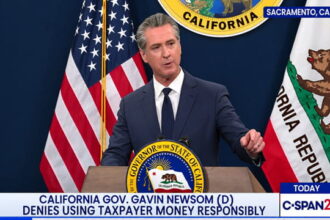 Gavin Newsom wearing a suit giving a speech on stage.