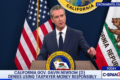 Gavin Newsom wearing a suit giving a speech on stage.