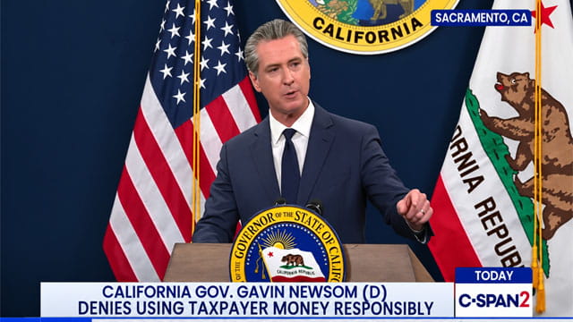 Gavin Newsom wearing a suit giving a speech on stage.