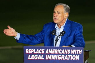 Republicans Greg Abbott on stage giving a speech on immigration.
