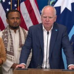 Minnesota Democrats Ilhan Omar and Tim Walz standing beside Somali men and women.