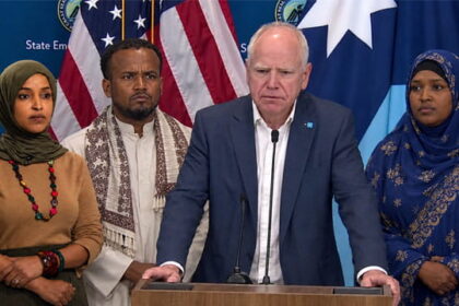 Minnesota Democrats Ilhan Omar and Tim Walz standing beside Somali men and women.