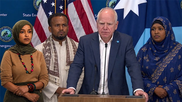 Minnesota Democrats Ilhan Omar and Tim Walz standing beside Somali men and women.