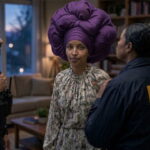 Ilhan Omar wearing a purple headscarf standing in living room surrounded by federal agents during a raid.