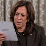 Kamala Harris staring at an Alaska ballot with a large bottle of wine on her table.