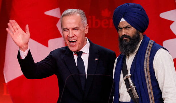 Canada Prime Minister Mark Carney standing next to an Indian Sikh man wearing a turban on stage.