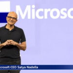 Bald male Indian Microsoft CEO on stage giving a speech.