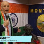 Montana Governor Gianforte wearing Indian clothes standing in front of a India flag.