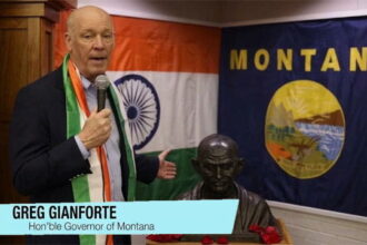 Montana Governor Gianforte wearing Indian clothes standing in front of a India flag.