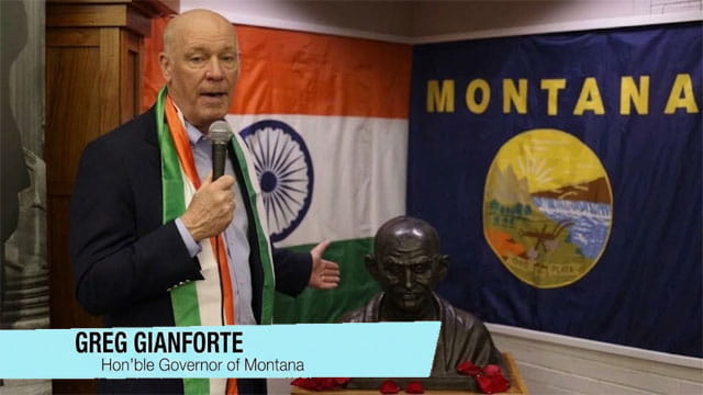 Montana Governor Gianforte wearing Indian clothes standing in front of a India flag.