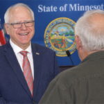 Tim Walz standing on stage in front of his old white-haired brother in Minnesota.