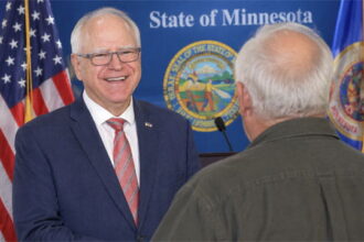 Tim Walz standing on stage in front of his old white-haired brother in Minnesota.