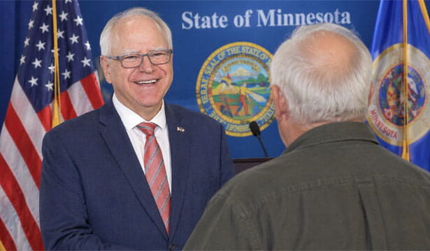 Tim Walz standing on stage in front of his old white-haired brother in Minnesota.
