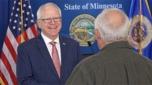 Tim Walz standing on stage in front of his old white-haired brother in Minnesota.