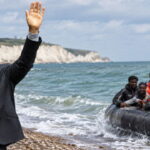 UK Prime Minister Andy Burnham waving to a group of African migrants on a boat.